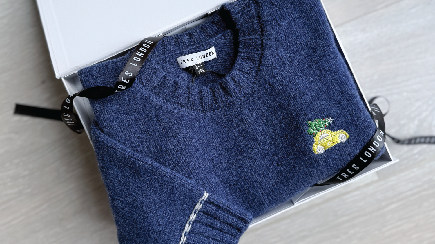 Christmas Jumper in lambswool for children, folded in a luxurious white gifting box.